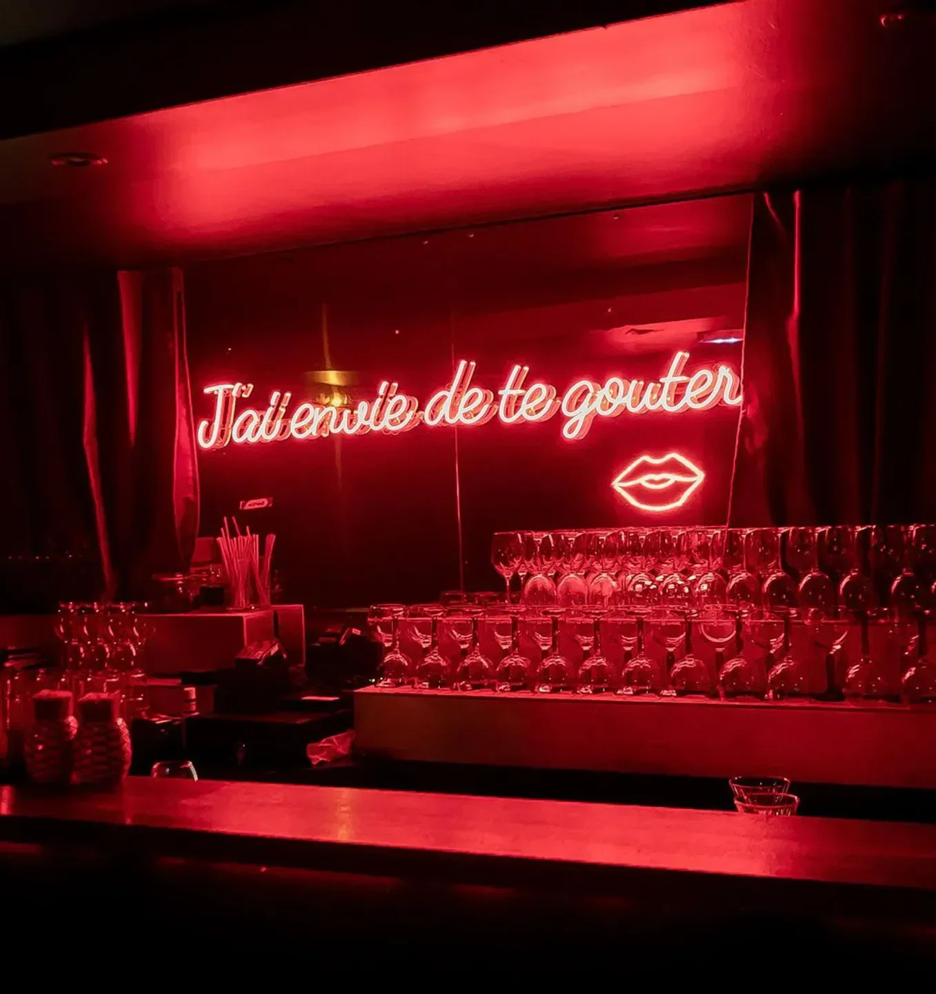 Neon sign inside Chez Moune nightclub in Paris, with red lighting and bar.
