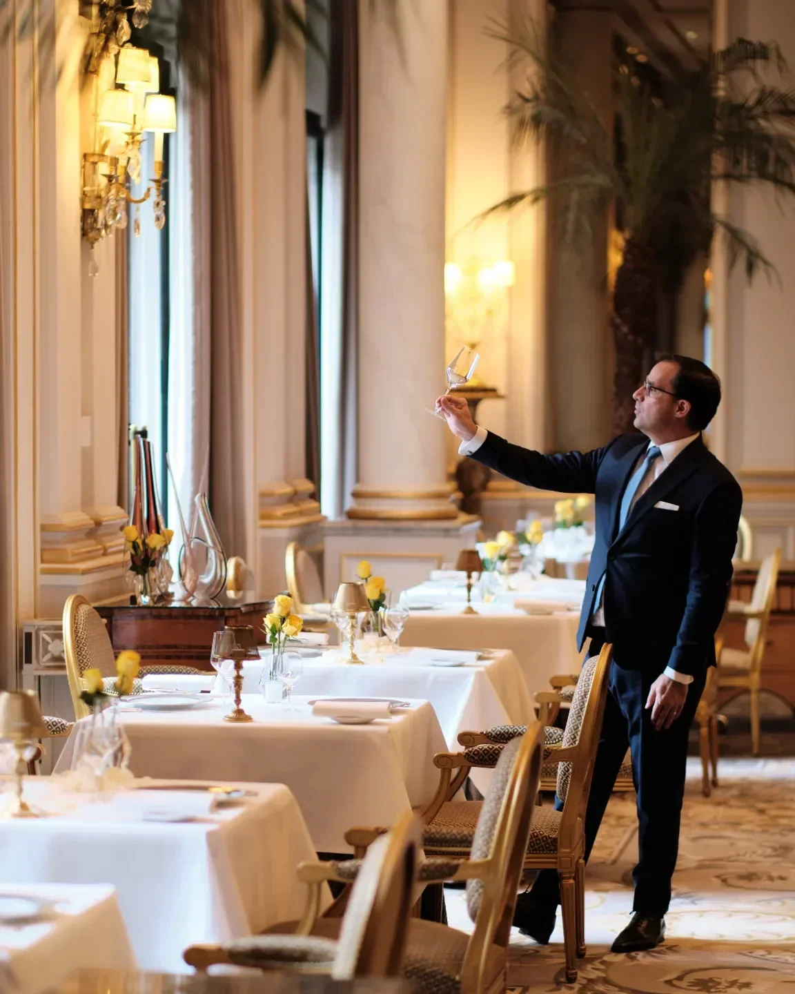 Sommelier inspecting a glass at Le Cinq restaurant in Paris, elegant dining experience.