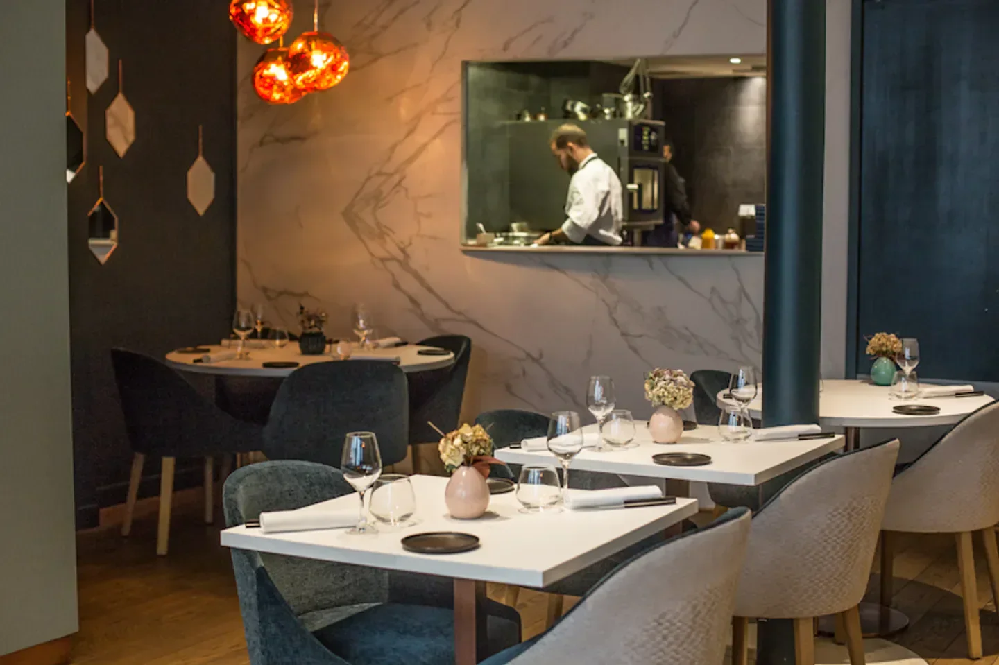 Elegant dining area at Restaurant H in Paris, with a view of the kitchen