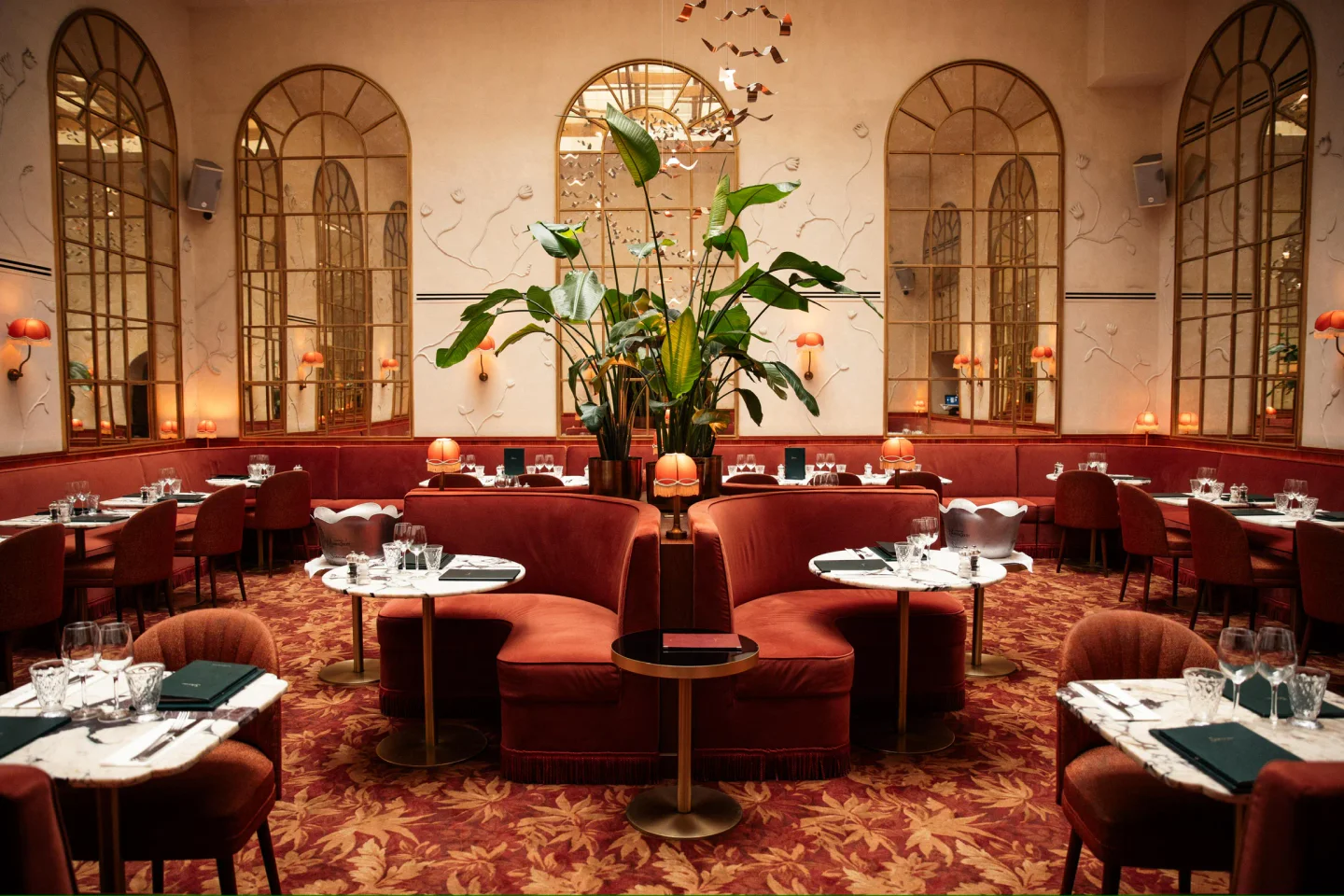 Siena restaurant in Paris featuring plush red banquettes, intricate mirrors, and elegant table settings.